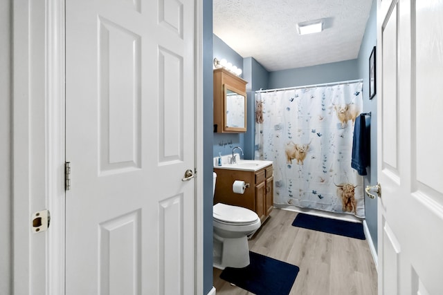 bathroom featuring hardwood / wood-style floors, a shower with shower curtain, vanity, a textured ceiling, and toilet