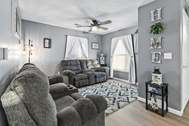 living room featuring ceiling fan, a textured ceiling, and light hardwood / wood-style floors