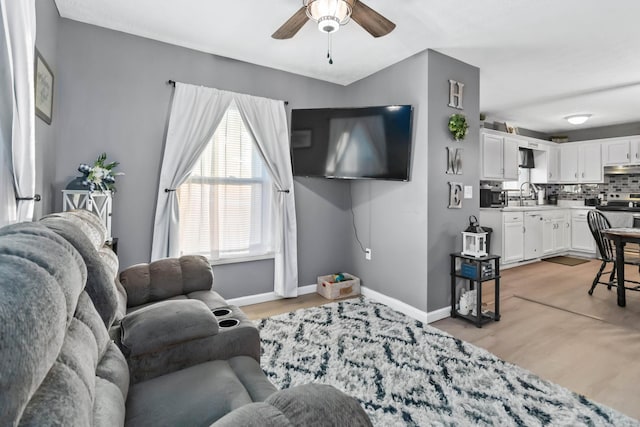 living room featuring sink, ceiling fan, and light hardwood / wood-style flooring