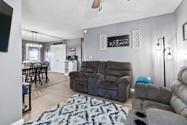 living room with wood-type flooring and ceiling fan with notable chandelier