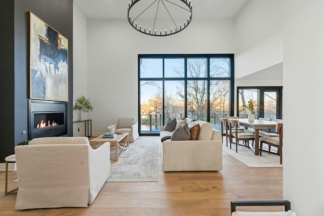 living area featuring a towering ceiling, a glass covered fireplace, and wood finished floors