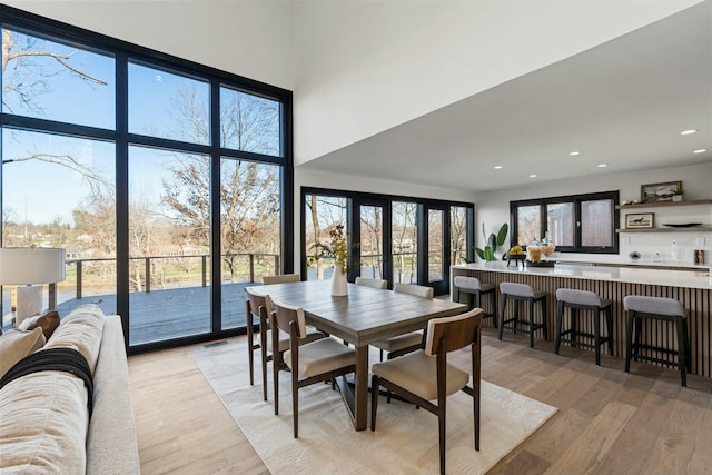 dining space with visible vents, a dry bar, recessed lighting, light wood finished floors, and a high ceiling