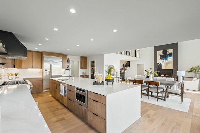 kitchen with custom exhaust hood, light wood-style floors, modern cabinets, and a sink