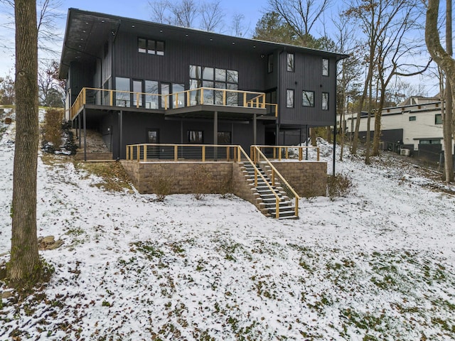 snow covered rear of property featuring a wooden deck