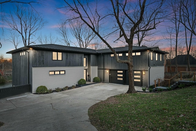 view of front of home with driveway, board and batten siding, a standing seam roof, metal roof, and a front lawn