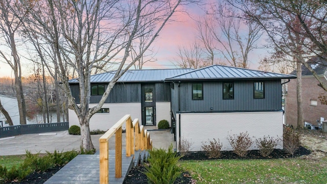 view of front of property with a standing seam roof, metal roof, and brick siding