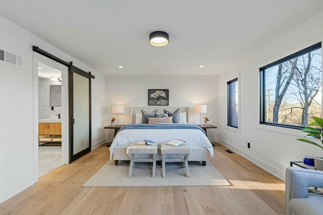 bedroom with visible vents, a barn door, light wood-style flooring, and recessed lighting