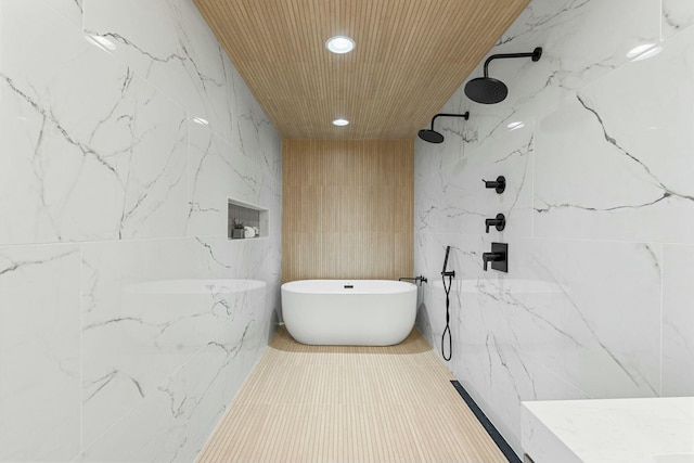 full bath featuring tile walls, recessed lighting, a freestanding bath, and a marble finish shower