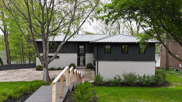 view of front of house featuring a standing seam roof, brick siding, a front yard, and metal roof