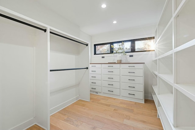 walk in closet with a barn door and light wood-type flooring