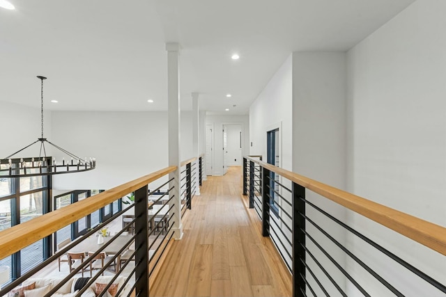 corridor featuring a chandelier, recessed lighting, light wood-type flooring, and an upstairs landing