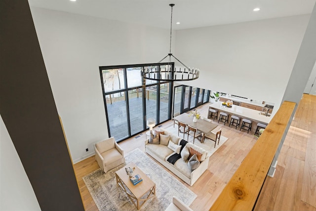 living area with recessed lighting, a towering ceiling, a chandelier, and light wood-style floors