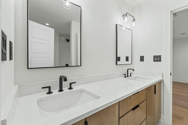 bathroom featuring visible vents, wood finished floors, double vanity, and a sink