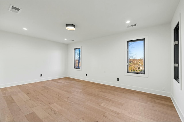 spare room with visible vents, plenty of natural light, light wood-style flooring, and baseboards