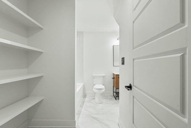 bathroom with toilet, marble finish floor, vanity, and baseboards
