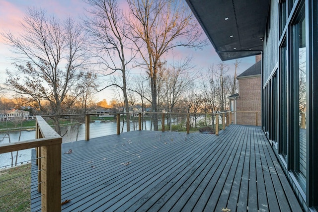 deck at dusk featuring a water view