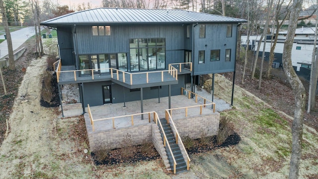 back of property with stairway, a standing seam roof, metal roof, and a patio area