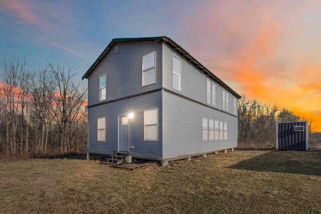 property exterior at dusk featuring a lawn