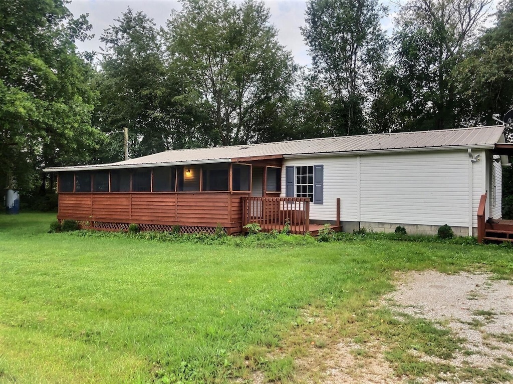 back of property with a wooden deck, a sunroom, and a yard