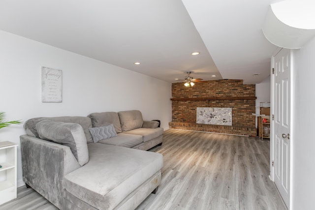 living room with brick wall, ceiling fan, and light hardwood / wood-style flooring