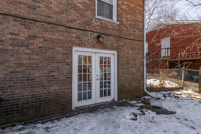 snow covered property entrance featuring french doors