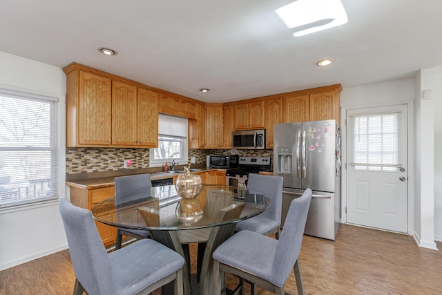 kitchen with sink, decorative backsplash, light hardwood / wood-style flooring, and stainless steel appliances