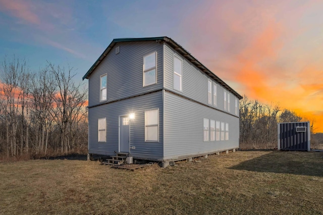 property exterior at dusk with entry steps and a yard