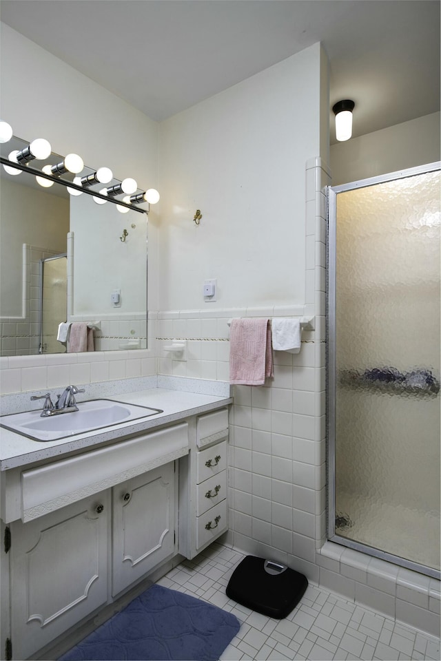 bathroom featuring tile patterned floors, a shower with door, tile walls, and vanity