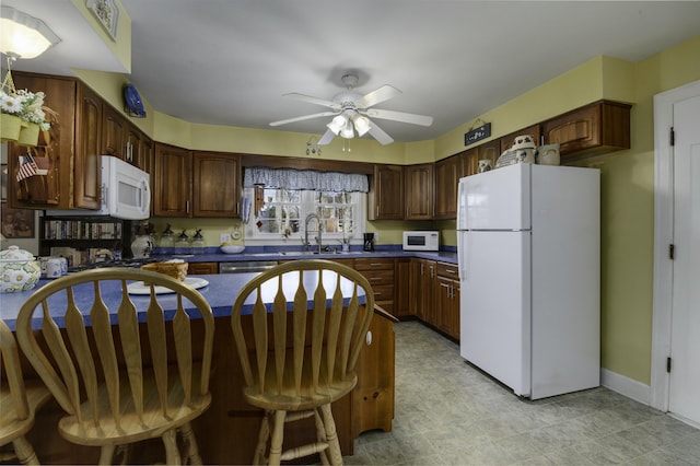 kitchen with ceiling fan, white appliances, dark brown cabinetry, and sink