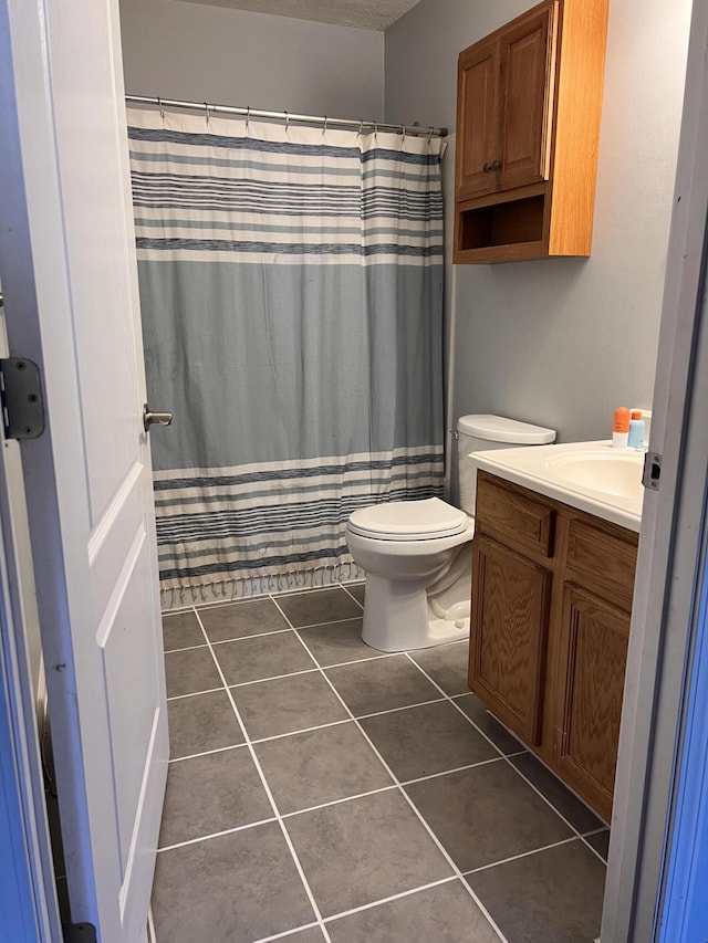 bathroom with tile patterned flooring, curtained shower, toilet, and vanity