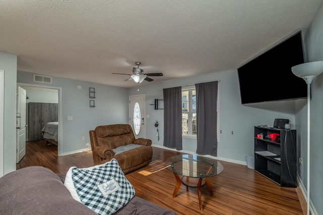 living room featuring ceiling fan, dark wood-type flooring, and a textured ceiling