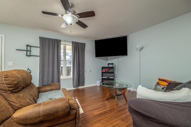 living area featuring hardwood / wood-style floors, a ceiling fan, baseboards, and a textured ceiling