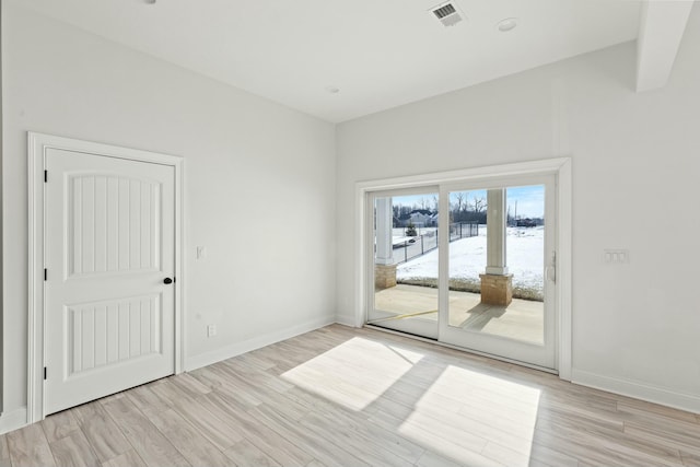 spare room with baseboards, visible vents, and light wood finished floors