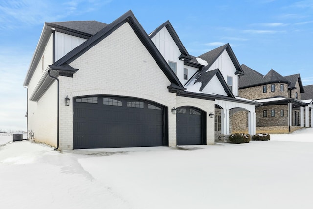 exterior space with board and batten siding, cooling unit, brick siding, and an attached garage