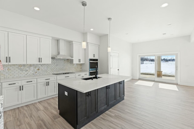 kitchen with wall chimney exhaust hood, black electric stovetop, stainless steel double oven, and white cabinetry