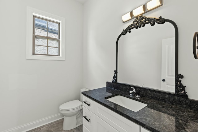 half bath with toilet, vanity, and baseboards