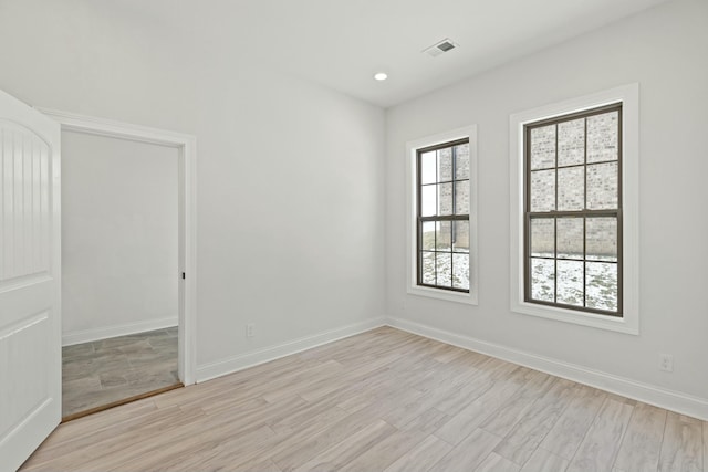 empty room featuring recessed lighting, light wood-type flooring, visible vents, and baseboards