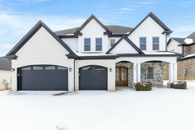 view of front of property featuring a garage, brick siding, board and batten siding, and french doors