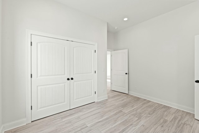 unfurnished bedroom with light wood-type flooring, baseboards, a closet, and recessed lighting