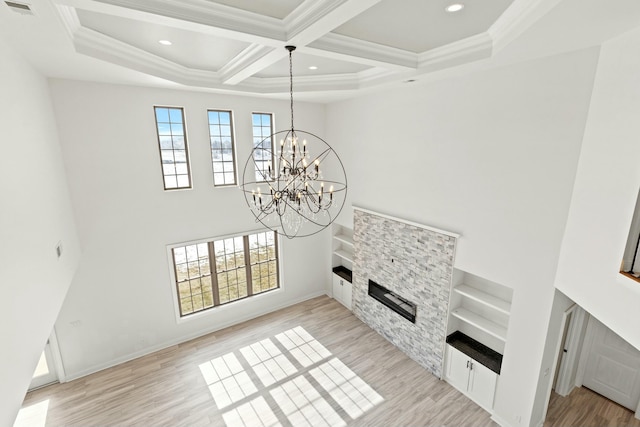 living area with a chandelier, ornamental molding, light wood-type flooring, and a fireplace