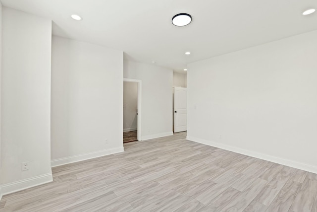 spare room featuring light wood finished floors, baseboards, and recessed lighting