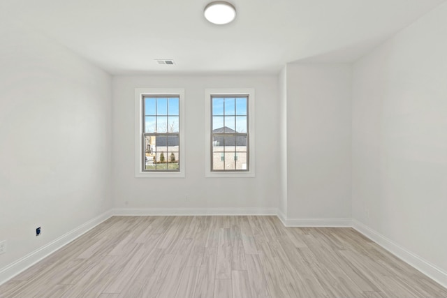 spare room with visible vents, light wood finished floors, and baseboards