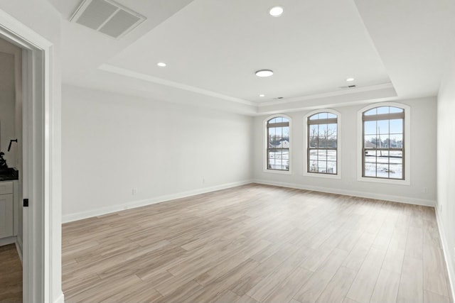 unfurnished room featuring visible vents, baseboards, light wood-style flooring, a tray ceiling, and recessed lighting