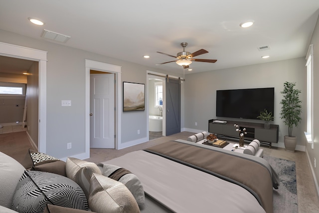 bedroom featuring ceiling fan, a barn door, and ensuite bath