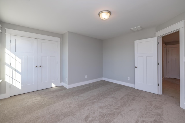 unfurnished bedroom featuring light colored carpet and a closet