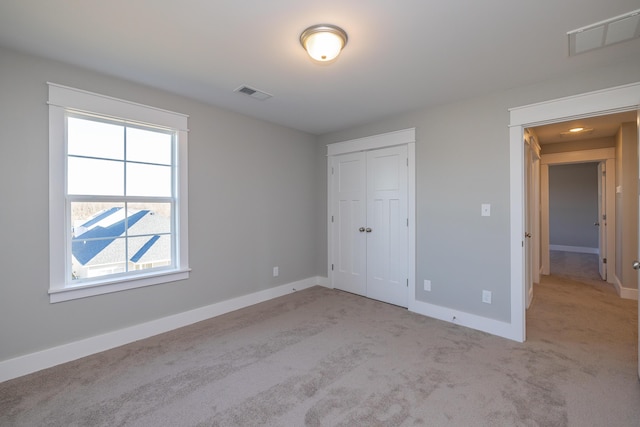 unfurnished bedroom with light colored carpet and a closet