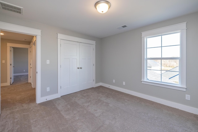 unfurnished bedroom with light carpet and a closet