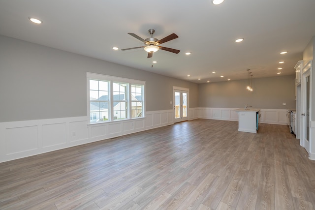 unfurnished living room with sink, ceiling fan, and light hardwood / wood-style flooring