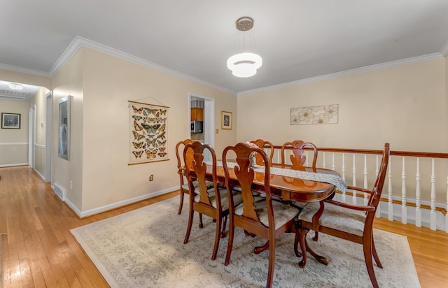 dining room with ornamental molding and light hardwood / wood-style floors