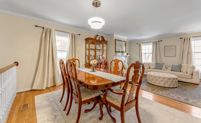 dining space with crown molding and light hardwood / wood-style floors